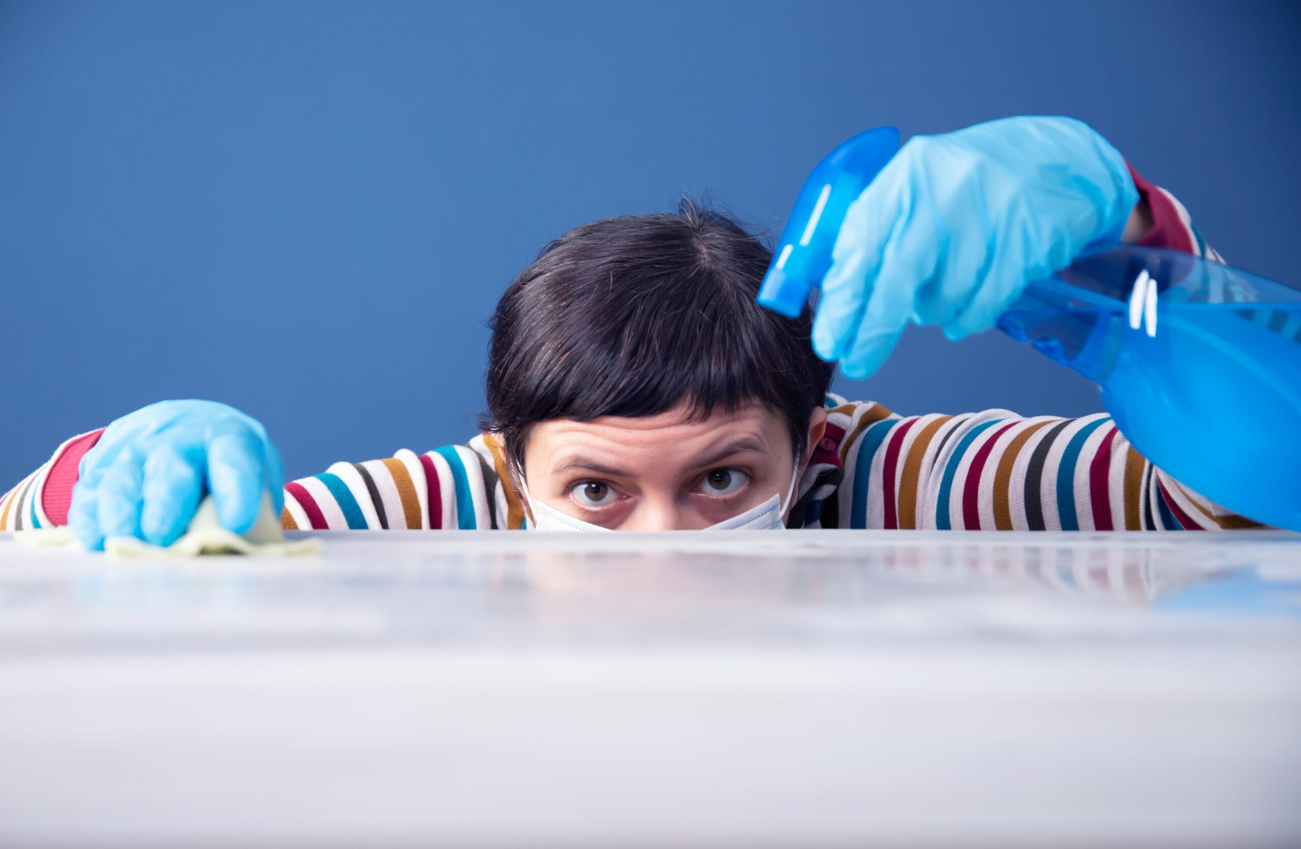 Woman cleaning and polishing the kitchen worktop with disinfectant spray. Coronavirus pandemic concept.
